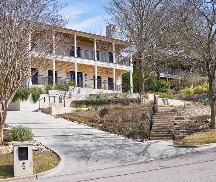 The front view of this beautiful Austin Stone home with hill country views with stunning wrap-around porches.